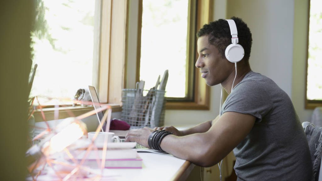 Student wearing headphones and using laptop to open a student checking account