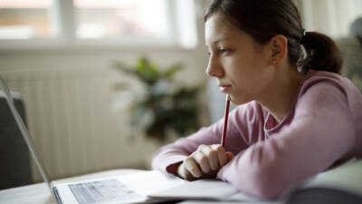 Bored teenage girl using laptop for studying at home